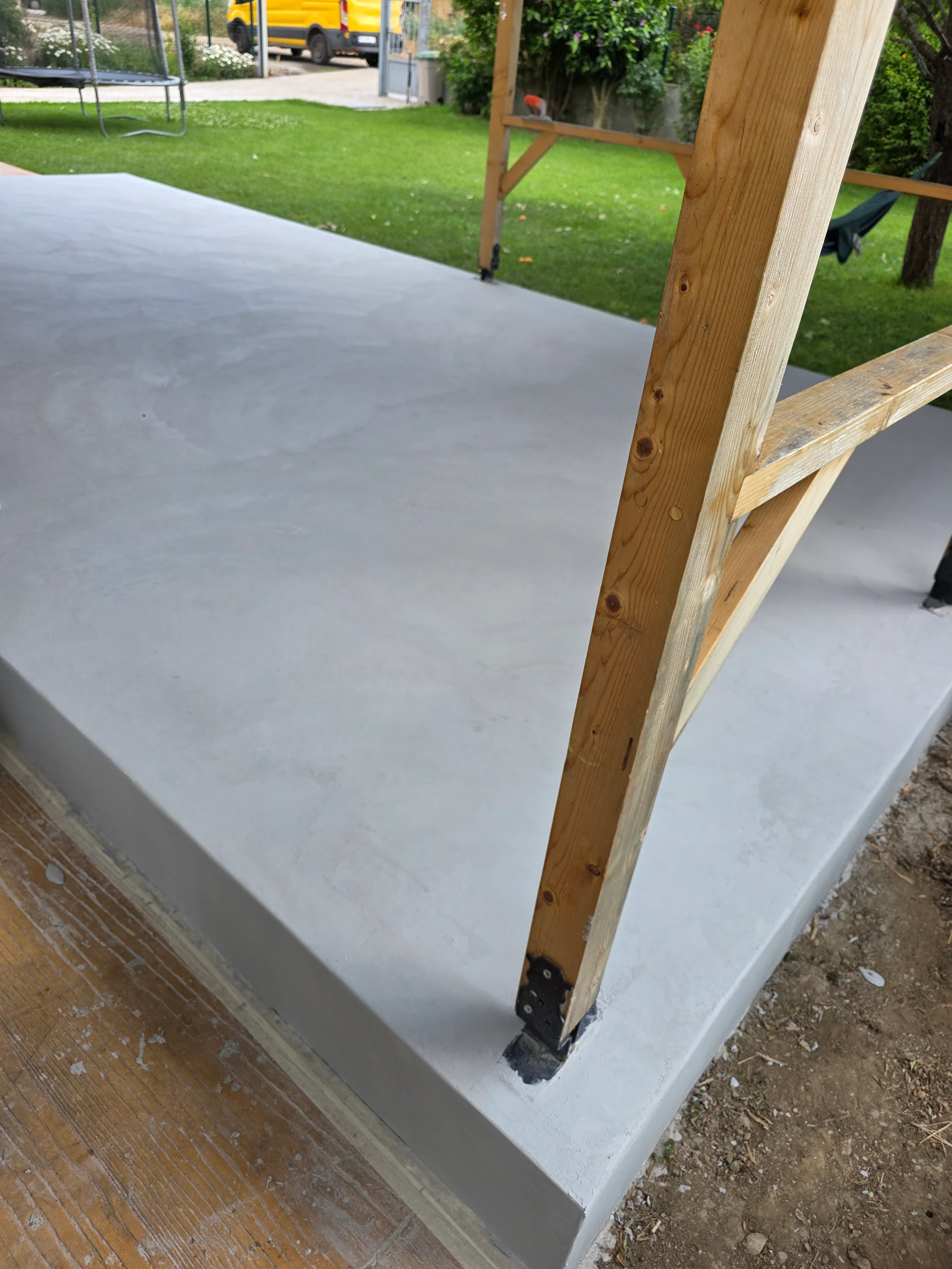 Floor coating around a timber support post and the veranda edge.